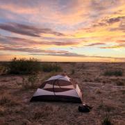 Goran's tent in a grassy area with a sunset in the background