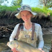 Martha holding a fish in a river