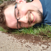 Photo of Alex Moss laying his head near a group of ants on the sidewalk
