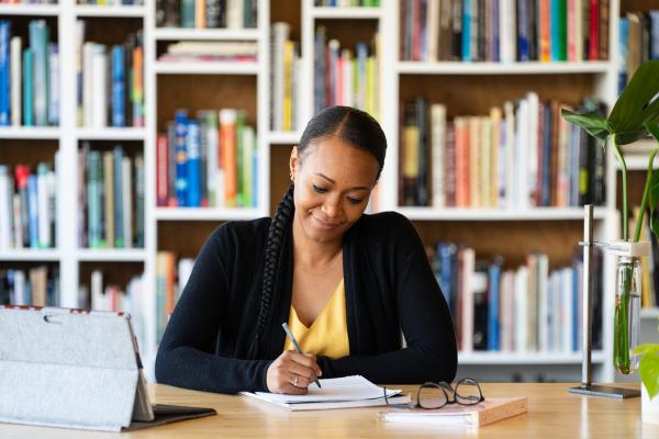 Student studying at a desk with books in the background.