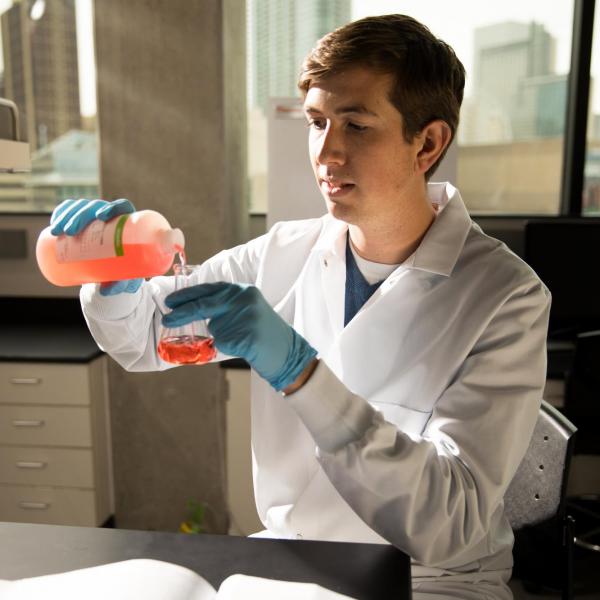 Student pouring chemicals into a flask