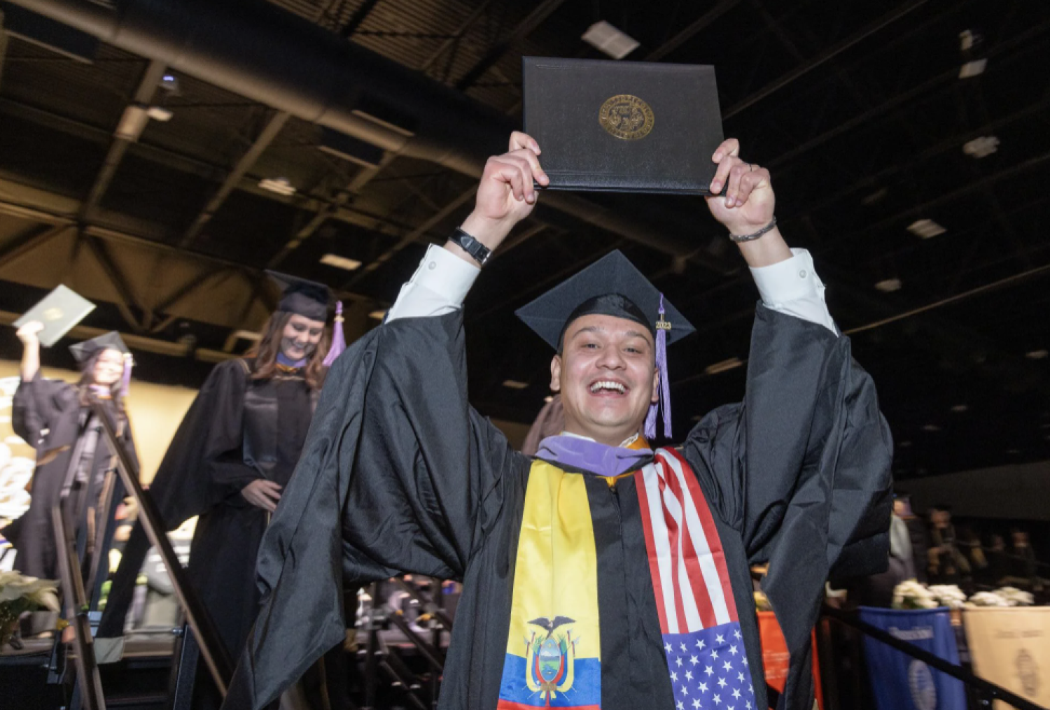 Student holding diploma over head smiling
