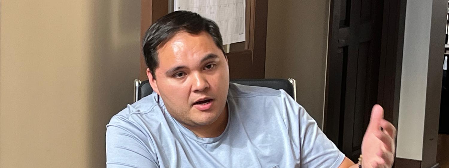 Man speaking in front of a laptop while seated at a table