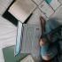 Above view of person studying cross-legged on bed with laptop and books
