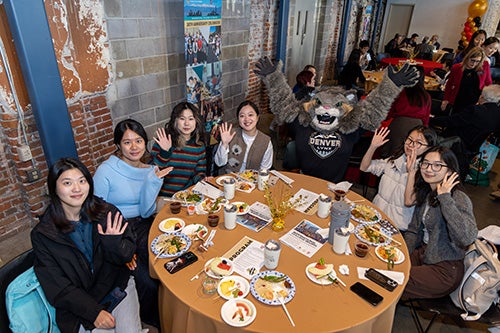 Students sit at a table waving