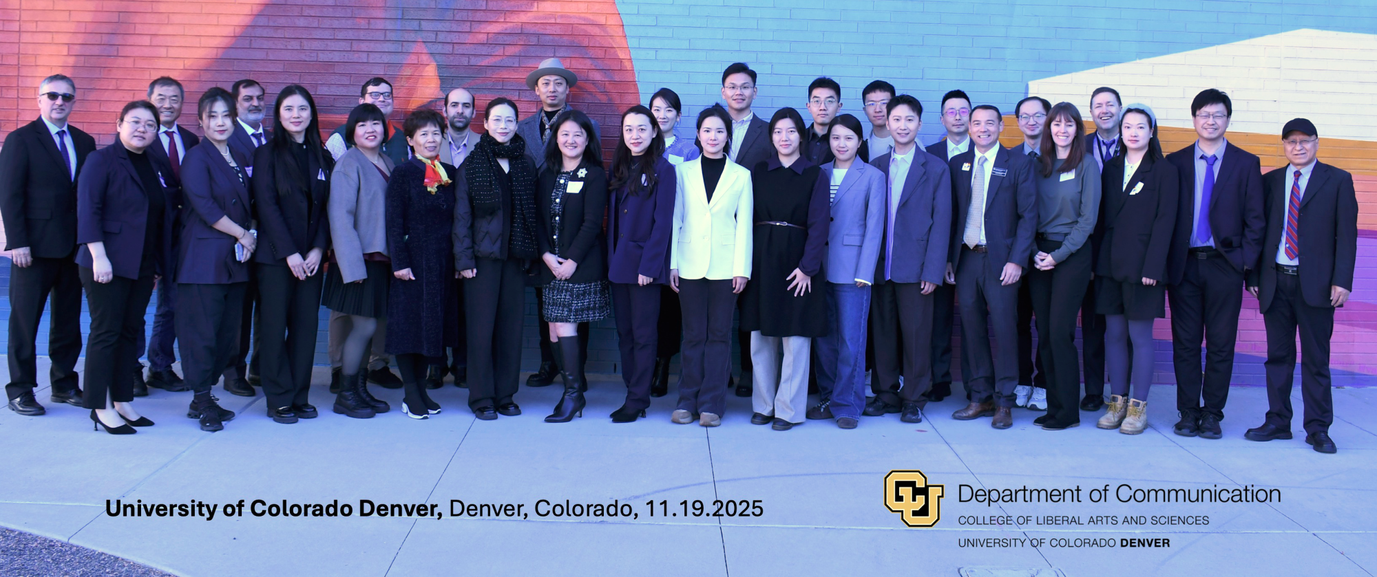 A group of approximately 30 visiting scholars and administrators from U.S. and Chinese universities stand together in front of a colorful mural at the University of Colorado Denver. They are posed in a single row, dressed in professional attire, smiling toward the camera. The CU Denver and Department of Communication logos appear at the bottom of the image along with the event location and date.