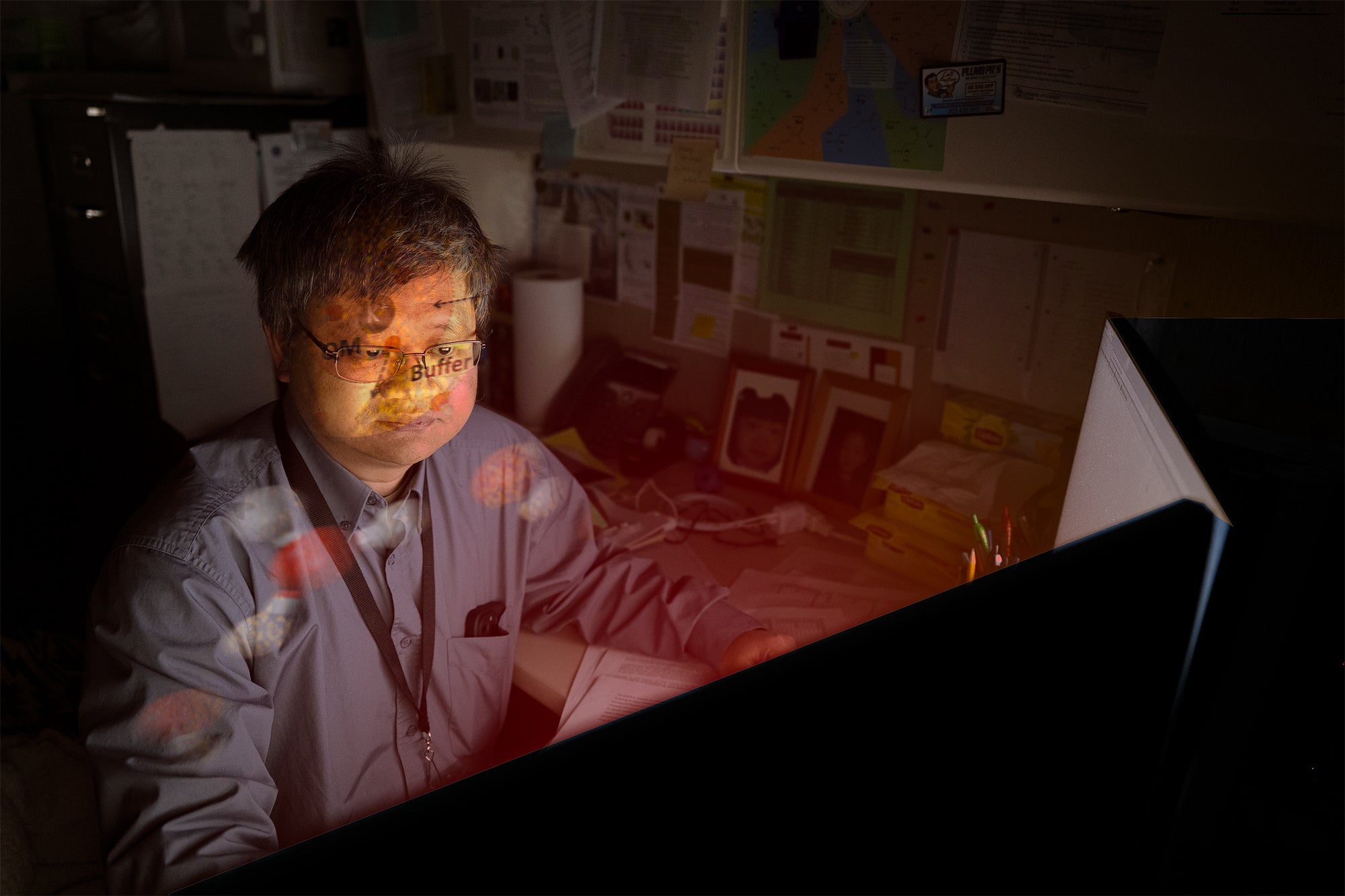 Hai Lin sits in front of glowing computer with imagery of atoms