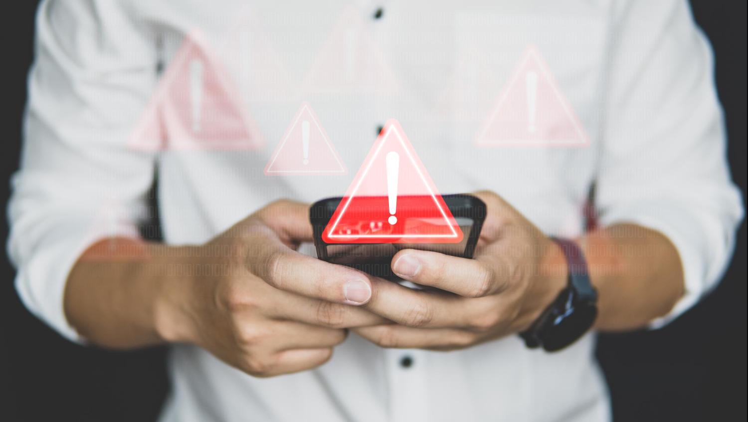man holds cell phone with warning image over the phone