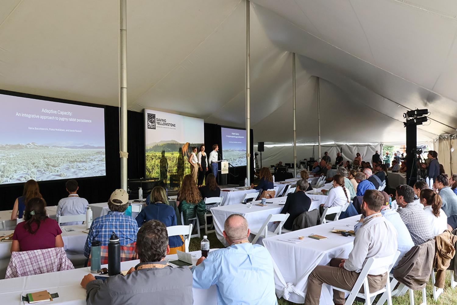 a wide shot of the summit attendees watching a presentation on stage