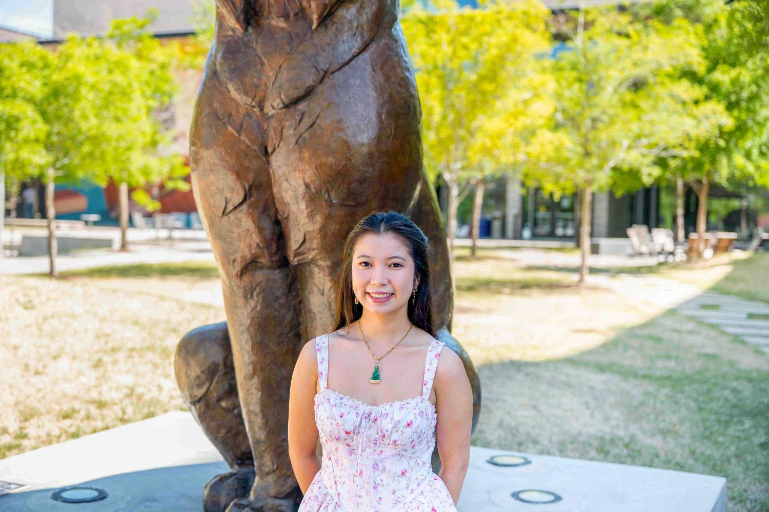 Kimmy stands in front of Milo the Lynx statue wearing a floral dress.