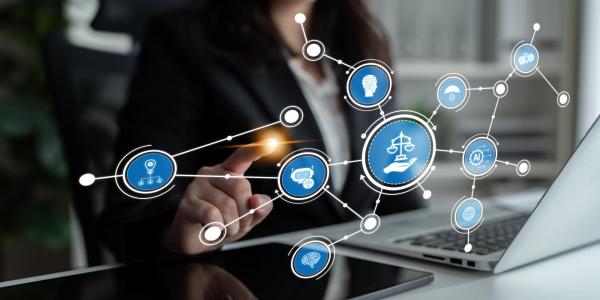 Person using a laptop with a digital display of interconnected AI and ethics icons centered around a balance scale symbol.