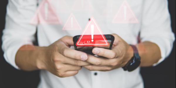 man holds cell phone with warning image over the phone