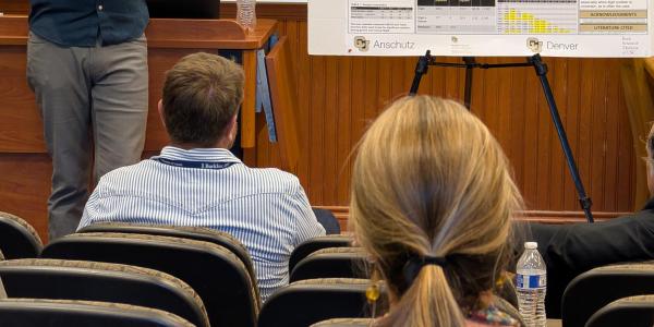 Dr. Caley Orr giving a presentation to a classroom of students. An easel is propped up displaying research.