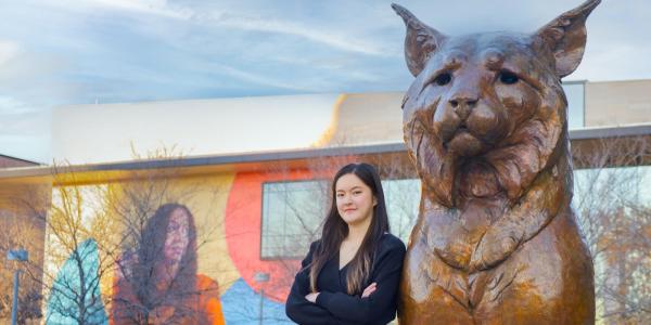 Junfei Liu leans against a bronze Milo statue.