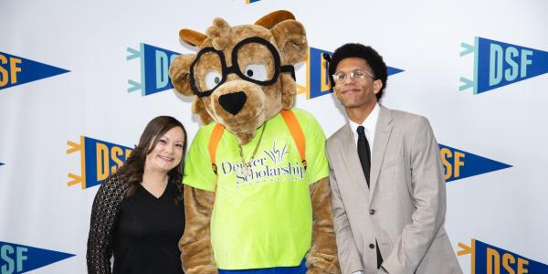 Michael Bourne, CU Denver student in International Studies and Latin American Studies, poses with the Denver Scholarship Foundation mascot and other speaker.