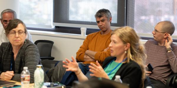 Anthropologists talk in a conference room and another looks on
