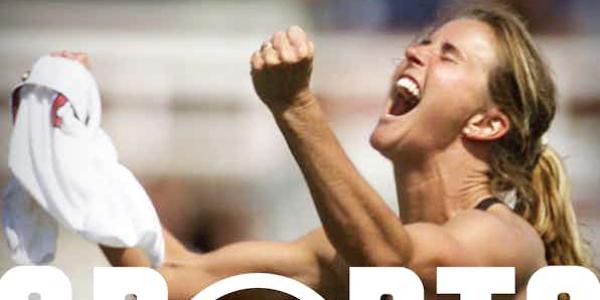 Kneeling female athlete celebrating win and clenching jersey in fist