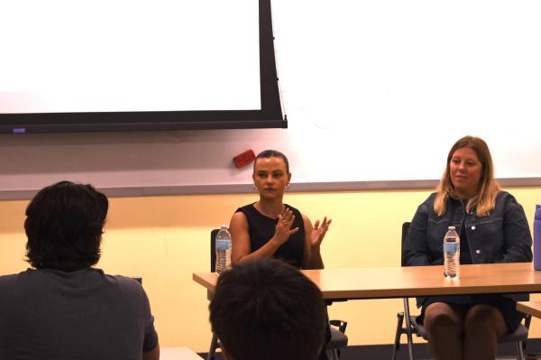 Shelby Cravens and Katie Stiffler sit at table talking to class