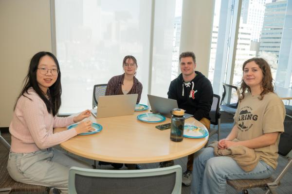 student sit at round table and smile a camera