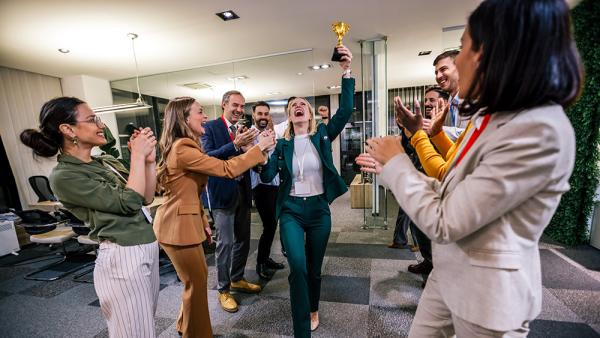 staff member holds up a trophy and others cheer