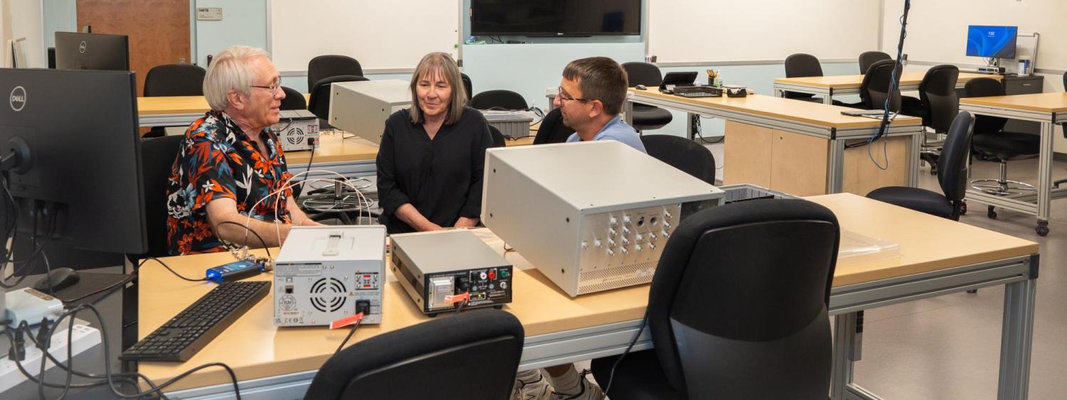 Martin, Cynthia, and Charles sit in quantum lab photo with wide angle