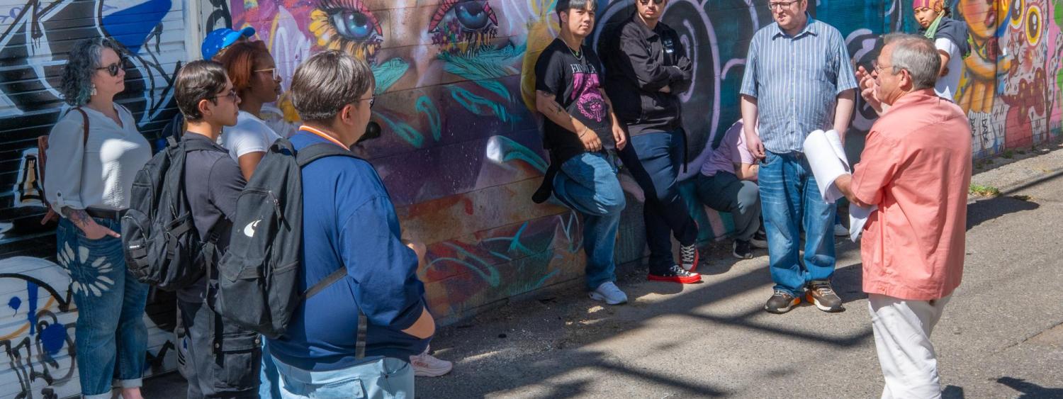 Students lean against mural listing to Tony