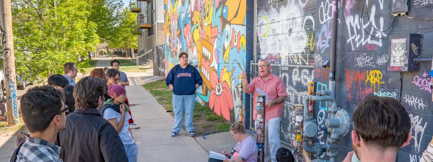 Prof. Tony speaks to students in front of another mural