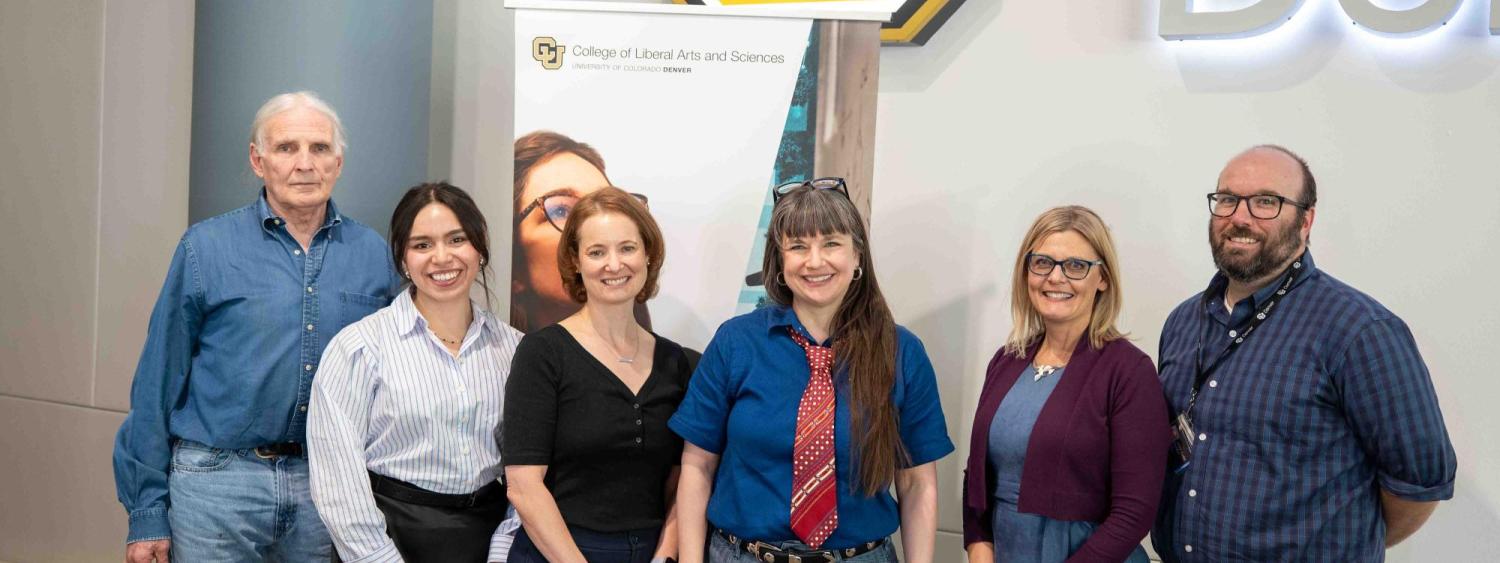 From left to right Jim Grigsby, Vanessa Navarro-Rodríguez, Anna Warrener, Nicky Beer, Lisa Keranen, and Michael Moore. They stand in front of a University of Colorado Denver sign and a banner for the College of Liberal Arts and Sciences