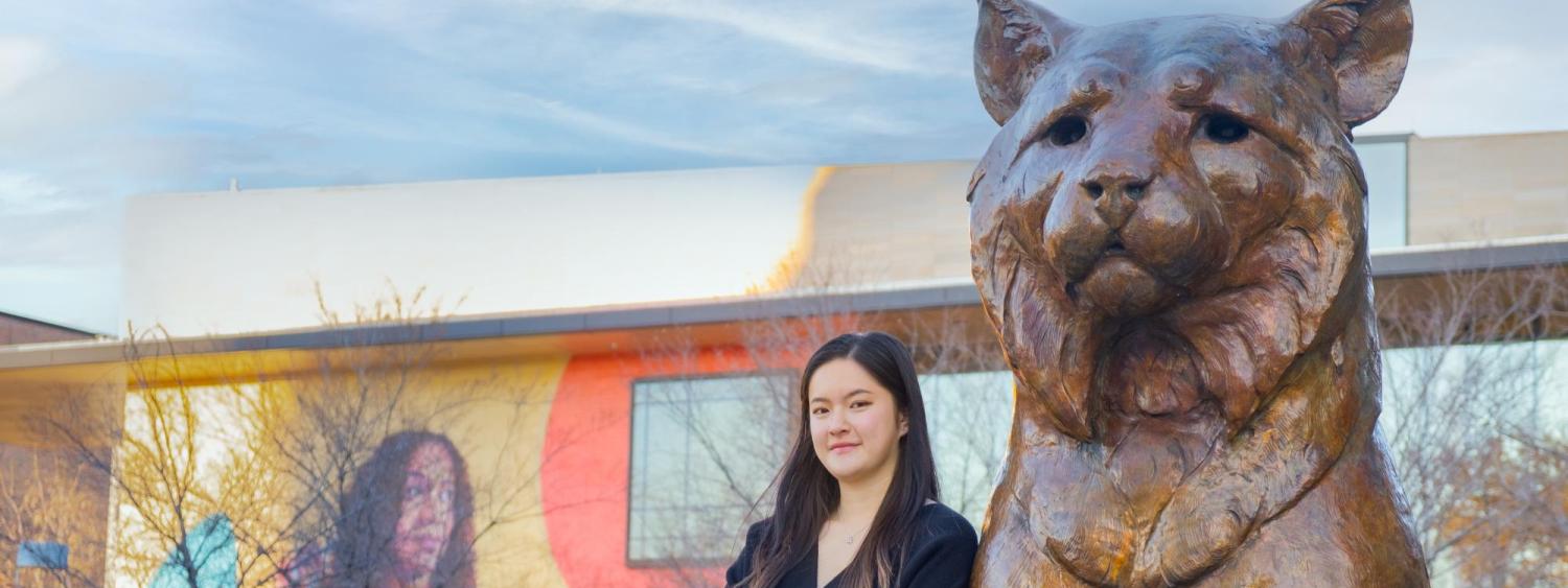 Junfei Liu leans against a bronze Milo statue.