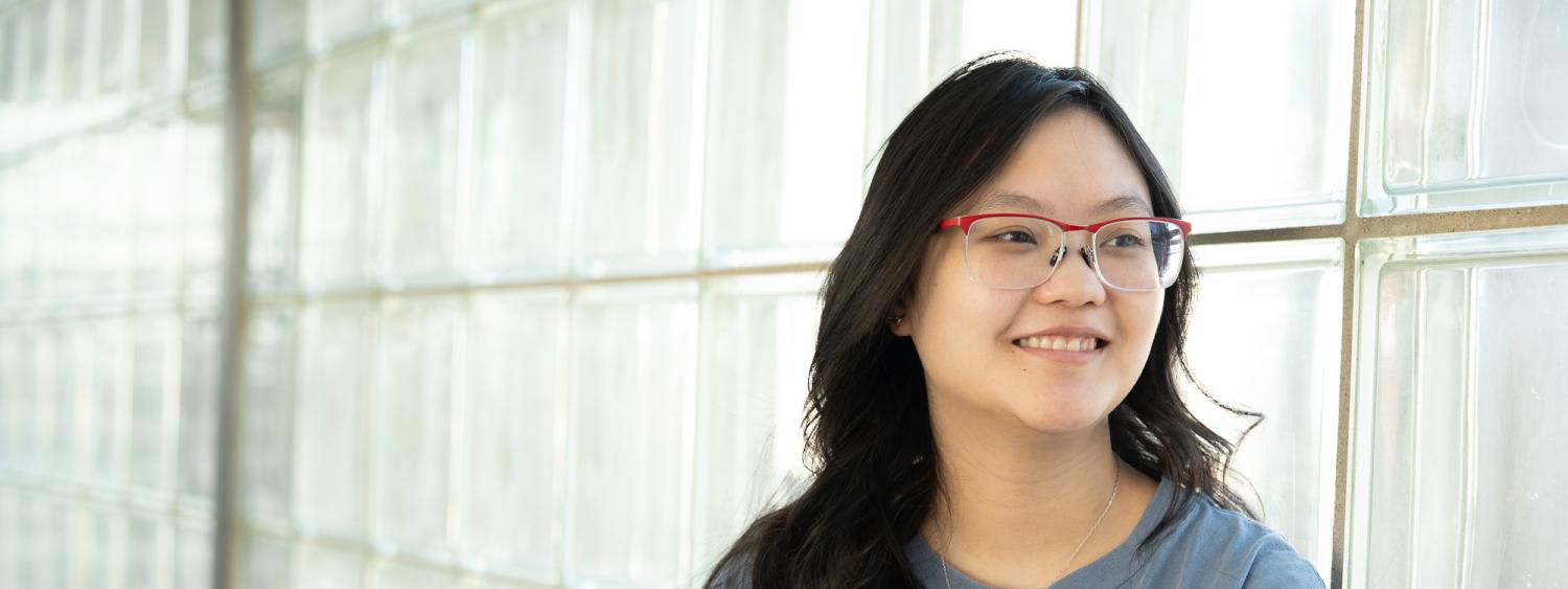 Abby Epstein looks off camera in hallway of glass
