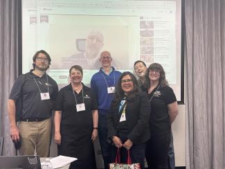 Carlock on the video screen behind CU Denver’s Kyle Danforth, Shana Medah, Sean Mueller, Regina Rodriguez, Stephen Hartnett, and Roxy New.