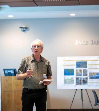 Martin Huber gives a presentation at CLAS Mixtape. He is wearing a green button up, black pants, and glasses.