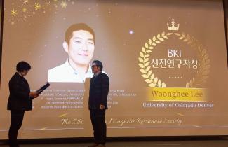 Professor Lee receiving the BKI Early Career Award, in front of a slide with his picture on it