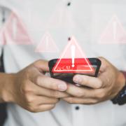 man holds cell phone with warning image over the phone