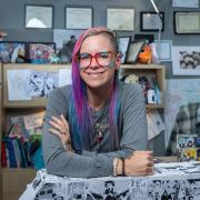 Emilie Waggoner surrounded by anime drawings in her office