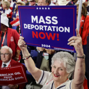 woman holds sign that reads Mass Deportation Now