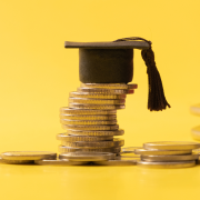 A graduation cap on top of quarters to imply the awarded grant money 