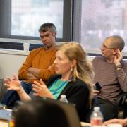 Anthropologists talk in a conference room and another looks on