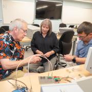 Martin, Cynthia, and Charles sit in quantum lab talking