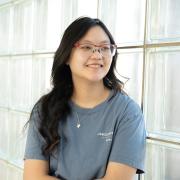 Abby Epstein looks off camera in hallway of glass