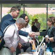 conference attendees shake hands with publishers in main hall