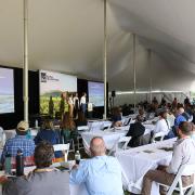 a wide shot of the summit attendees watching a presentation on stage