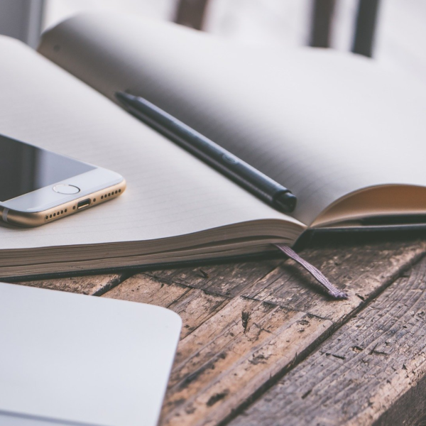 Laptop, notebook, pen, and smart phone on a wooden table