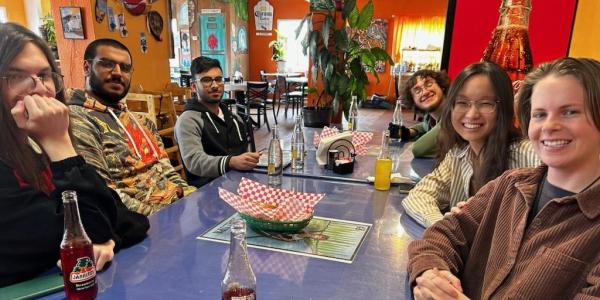 Students on trip smiling while sitting at the table for a meal