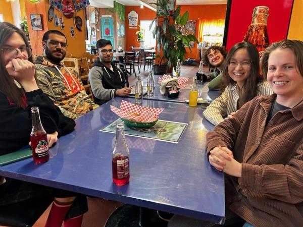 Students on trip smiling while sitting at the table for a meal