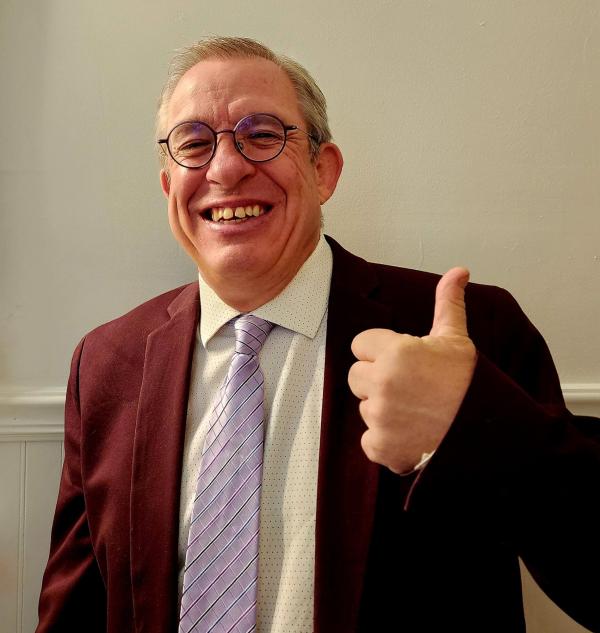 Photo of Political Science Department  Chair, Tony Robinson, in purple suit jacket and giving a thumbs up sign