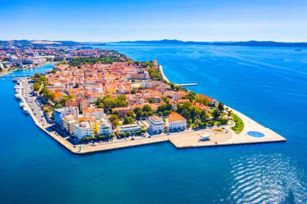 Picture of dense, picturesque European village of red roof buildings clustered on a small island on a deep blue sea