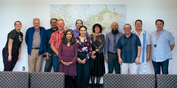 Photo of many individuals standing in front of a world map