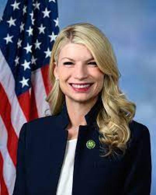 Rep Pettersen smiling in front of an American Flag