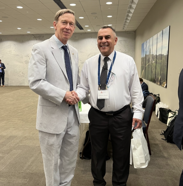 Ali Alnazzal shaking hands with an attendee, smiling